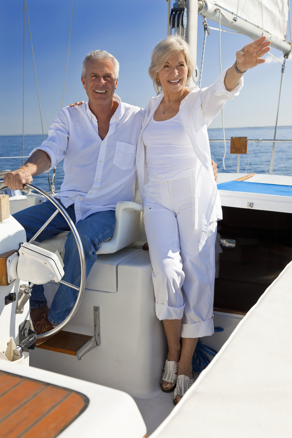 iStock-149258108 A happy senior couple sitting at the wheel of a sail boat on a calm blue sea